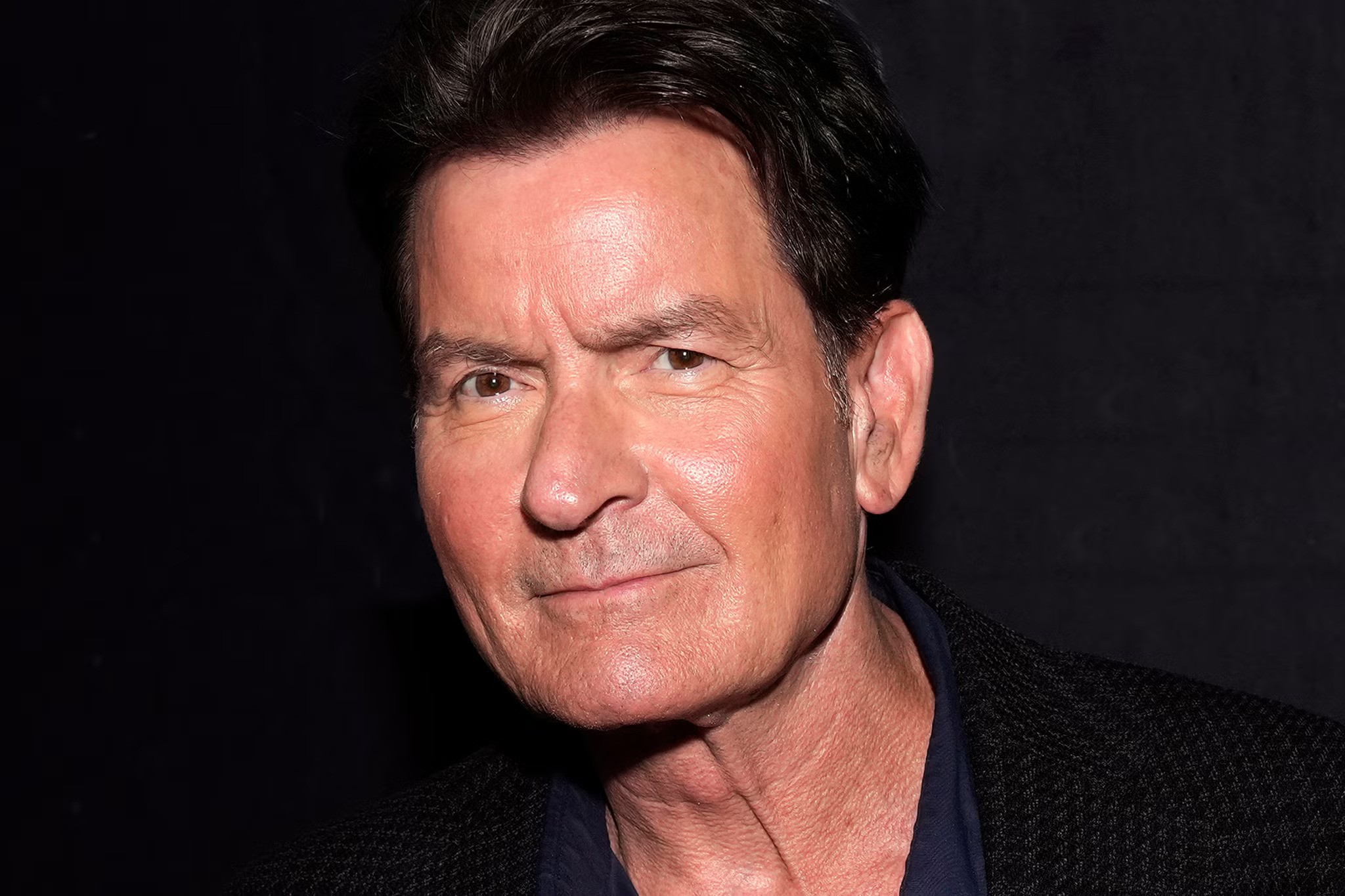Charlie Sheen wearng black and blue looking at the camera