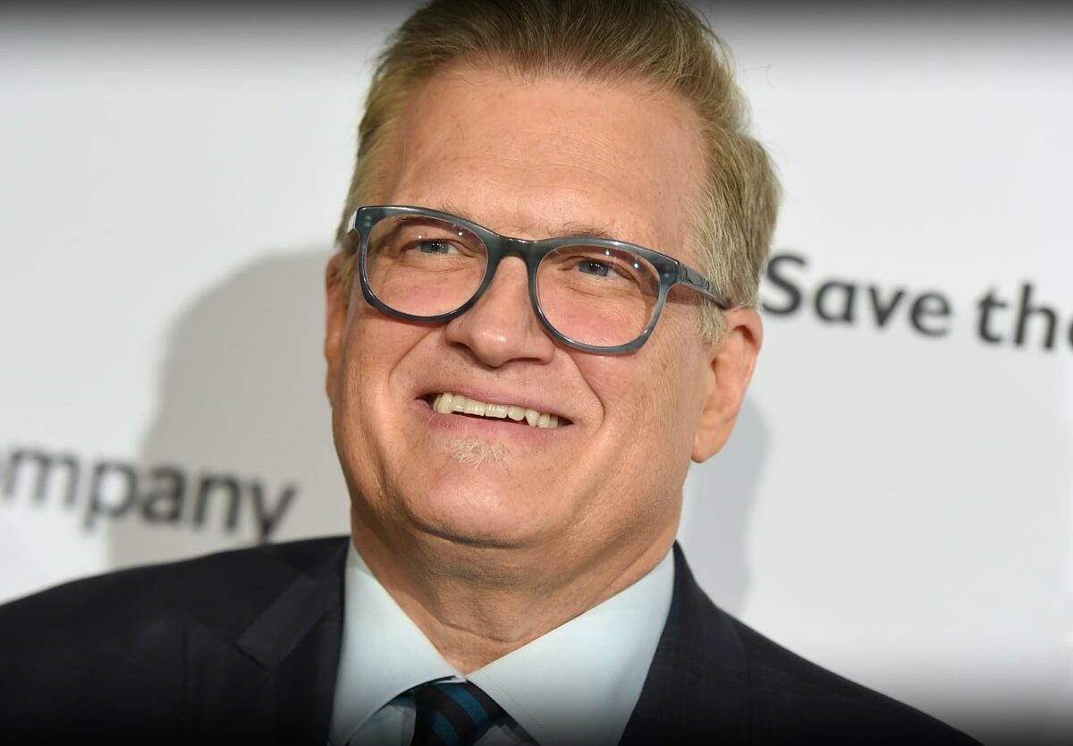 Drew Carey in a suit and glasses smiling warmly at the camera.