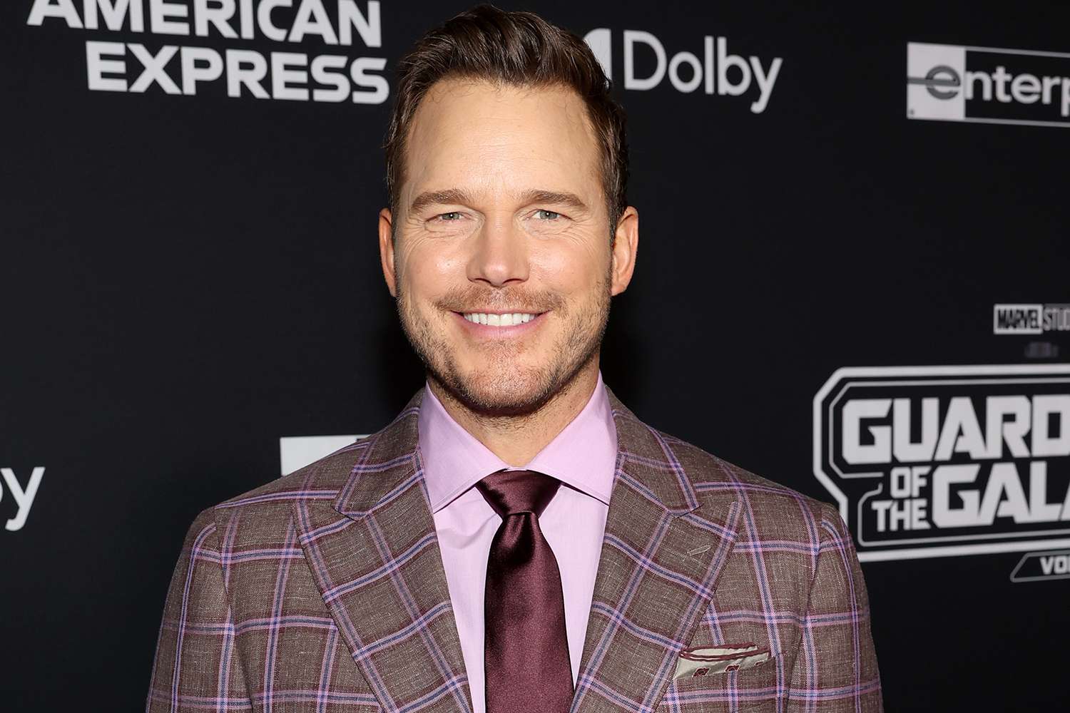 Chris Pratt in a formal suit and tie, posing confidently