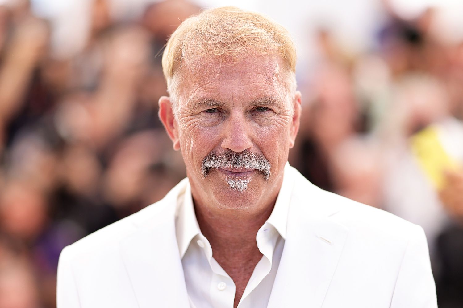 Kevin Costner with a mustache wearing a white suit