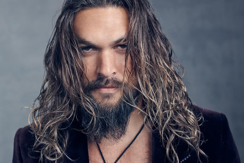Jason Momoa has long, curly hair that cascades down his shoulders.